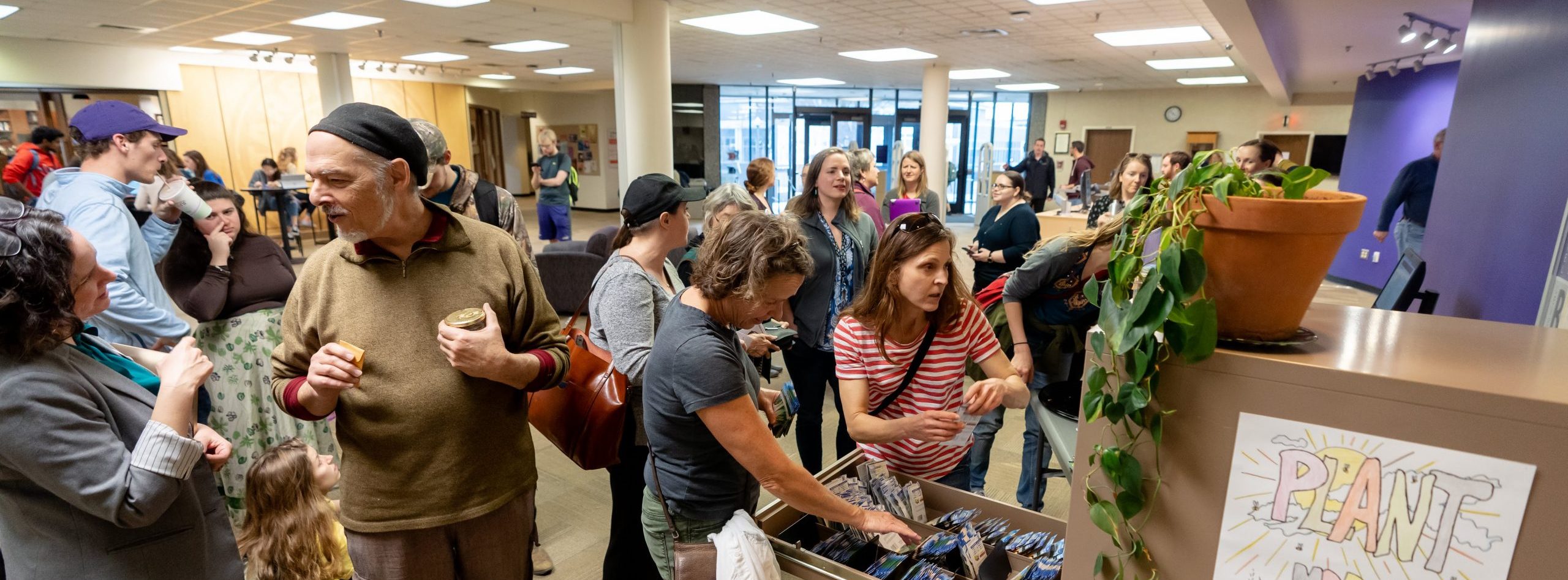 A group of people gather inside Carrier Library to see the Community Seed Library.